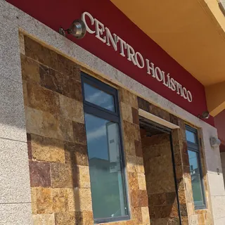 La entrada del centro desde la calle, con el rótulo «Centro Holístico» sobre la fachada de piedra